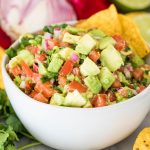 avocado salsa in white bowl with corn chips