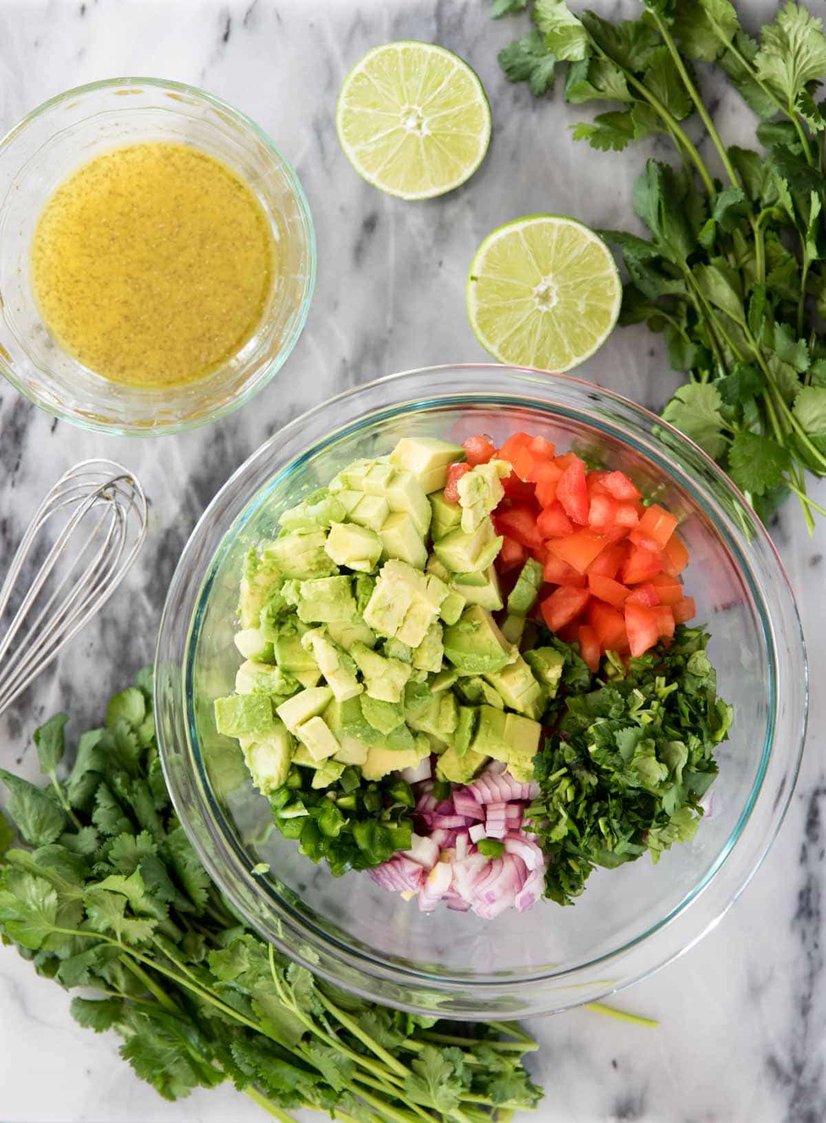 overhead of ingredients: vegetables in glass bowl, dressing in small separate bowl