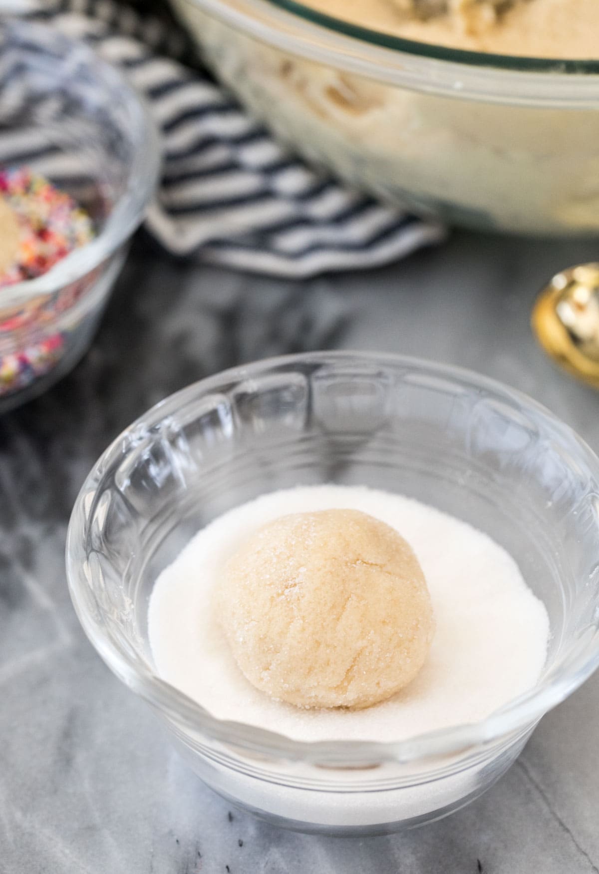 rolling cookie dough ball through granulated sugar
