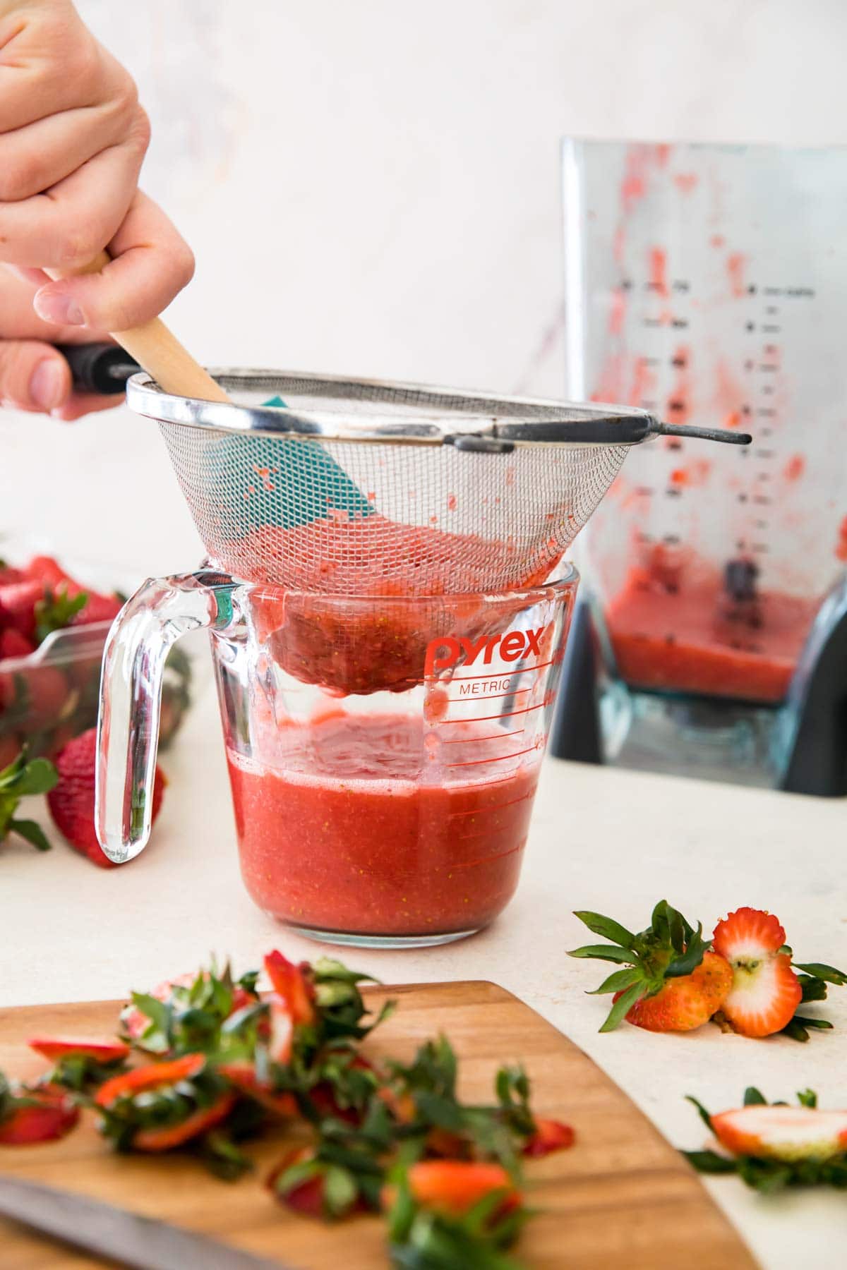 straining pureed strawberries into measuring cup