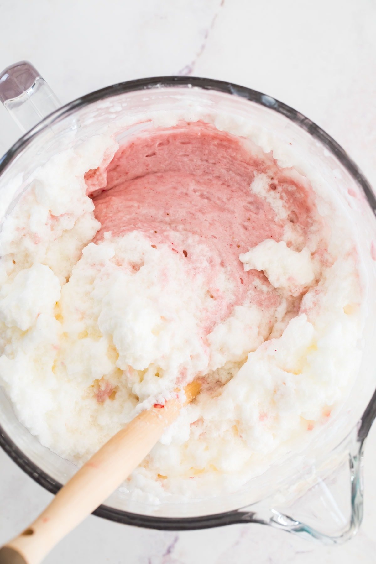 Stirring whipped egg whites into pink cake batter