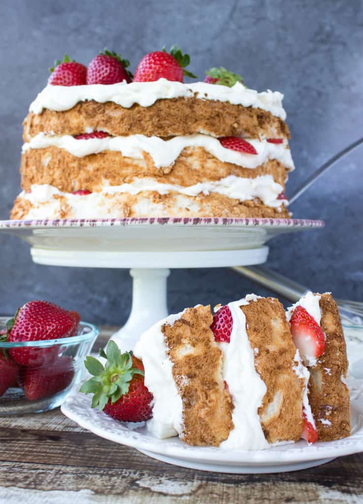 Lemon Layered Angel Food Cake slice in foreground, whole cake in background