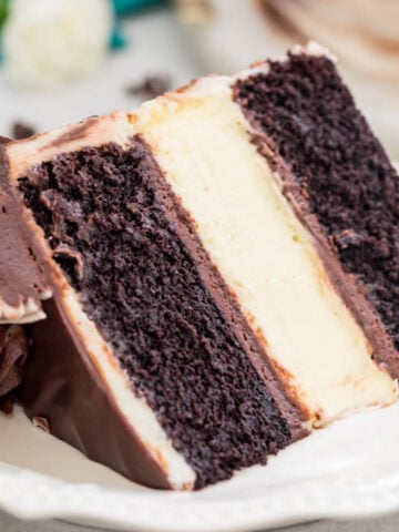 slice of cheesecake stuffed cake with clear, defined layers of dark chocolate cake and classic cheesecake on a white plate
