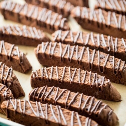 chocolate drizzled chocolate biscotti cookies arranged on a baking sheet