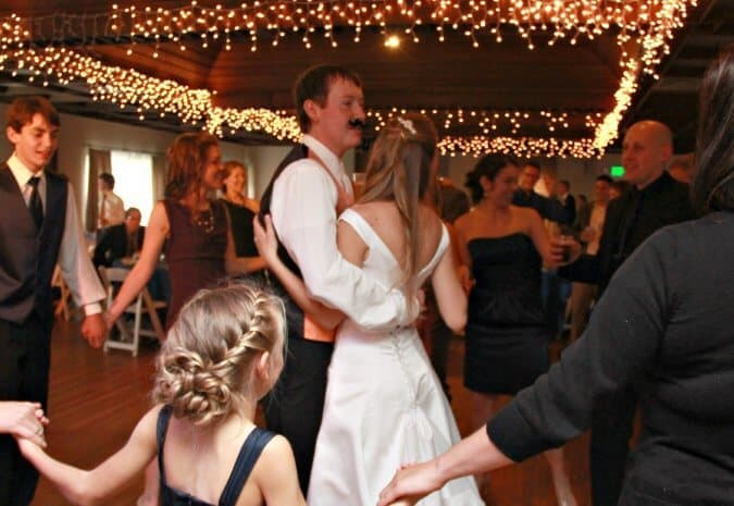 bride and groom (wearing a fake moustache) dance at wedding reception