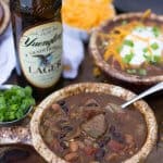 Steak and beer chili in a bowl, bottle of beer in background
