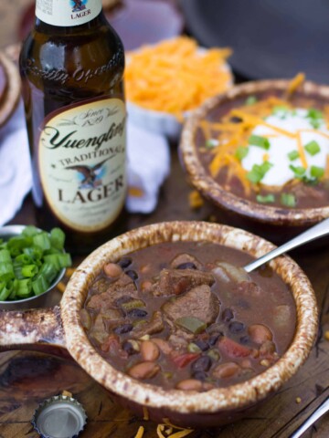Steak and beer chili in a bowl, bottle of beer in background