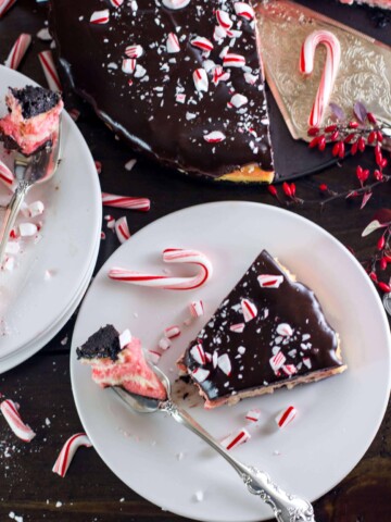 Slice of candy cane mint cheesecake on a plate with the entire cake in the background