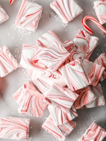 Overhead of a pile of red-swirled peppermint marshmallows on marble