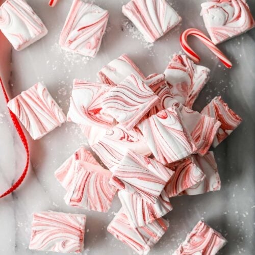 Overhead of a pile of red-swirled peppermint marshmallows on marble