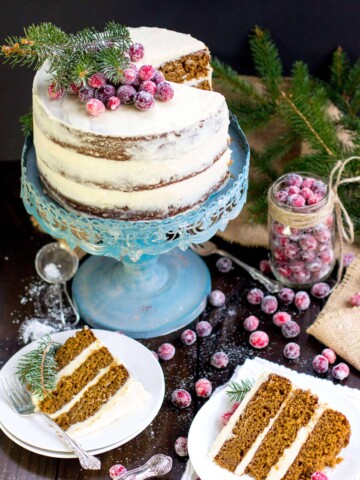 Frosted Gingerbread layer cake on a blue cake stand with slices on white plates