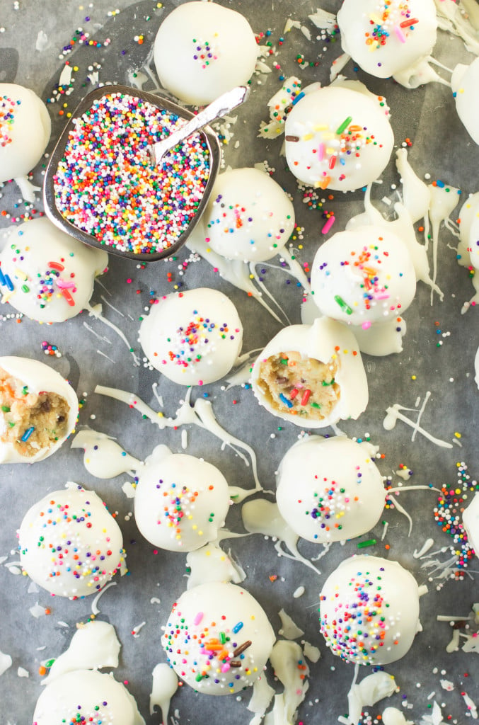 Golden oreo truffles with sprinkles and white chocolate splashes on wax paper 