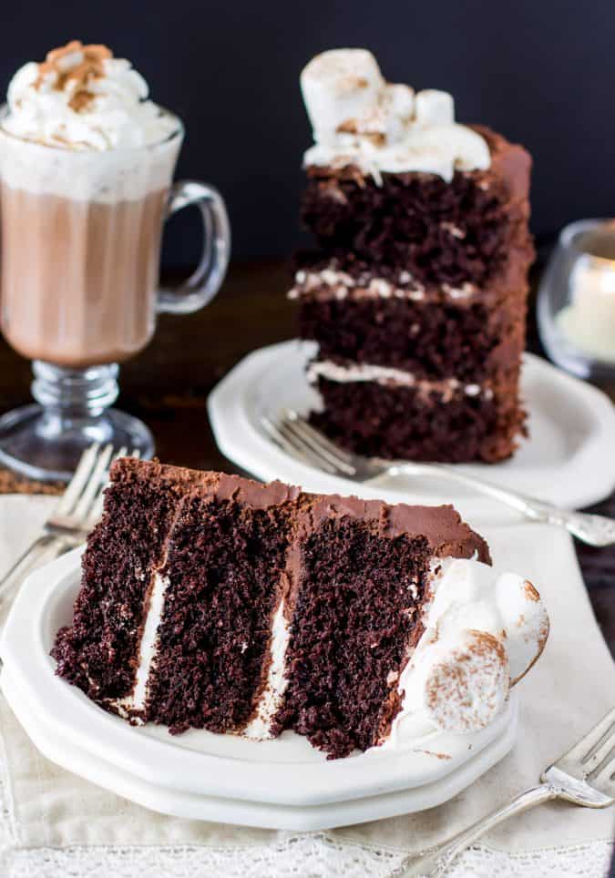 slice of cake on white plate with hot cocoa in the background