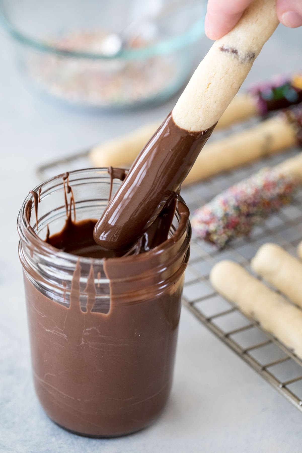 dipping a cookie stick into a jar of chocolate