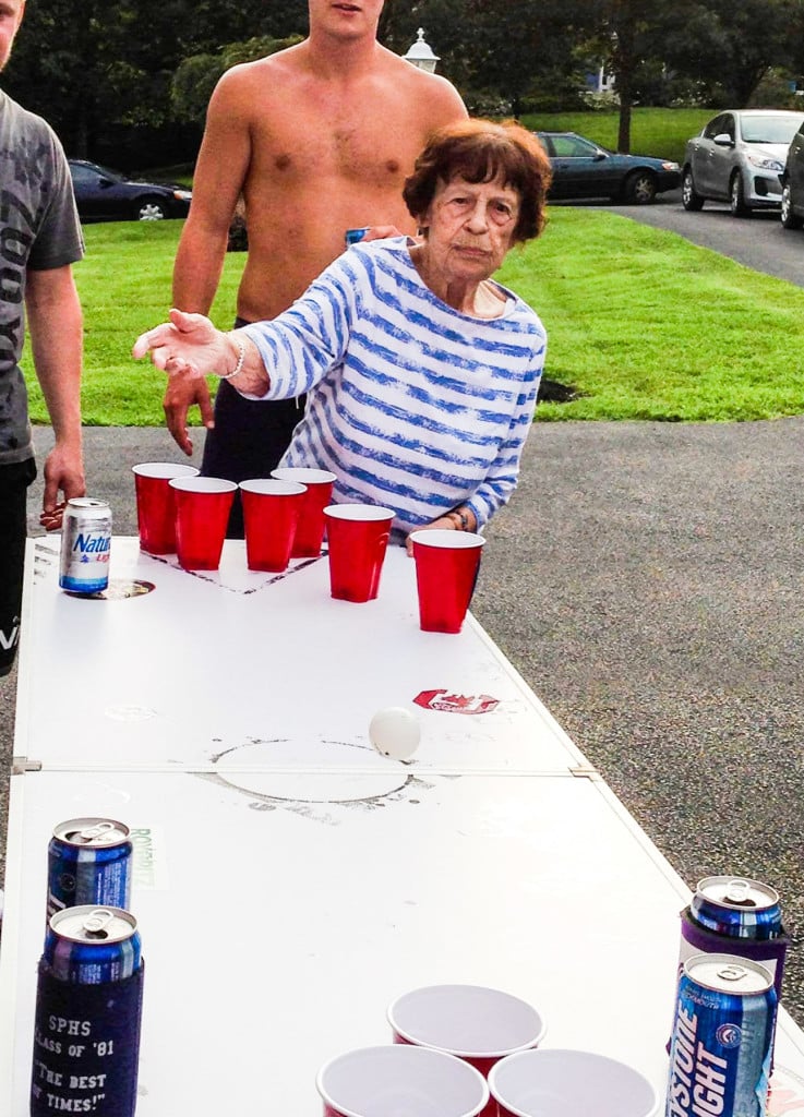 bisabuela jugando al pong de cerveza con un estudiante universitario sin camisa de fondo