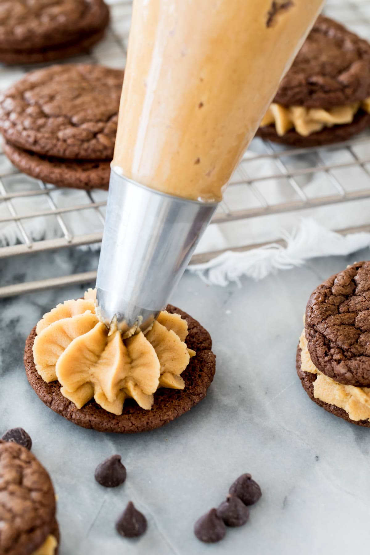 piping peanut butter frosting on chocolate cookie