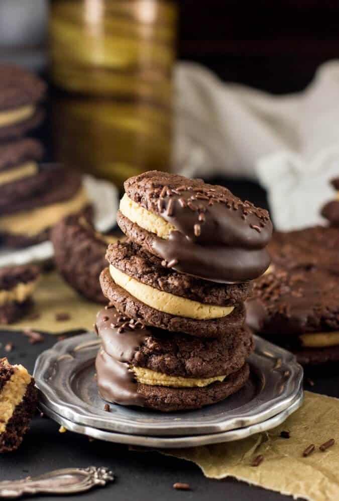 Stack of three chocolate dipped chocolate peanut butter sandwich cookies on a silver plate