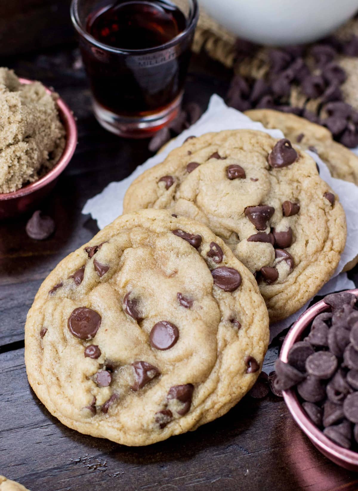 Two chewy chocolate chip cookies on a dark backdrop