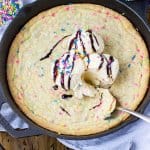 Funfetti blondie topped with scoops of vanilla ice cream in a skillet