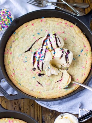 Funfetti blondie topped with scoops of vanilla ice cream in a skillet