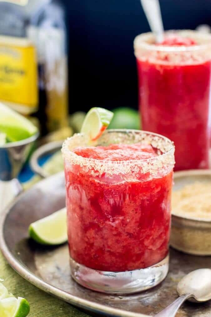 Strawberry margarita granita in a glass with a slice of lime