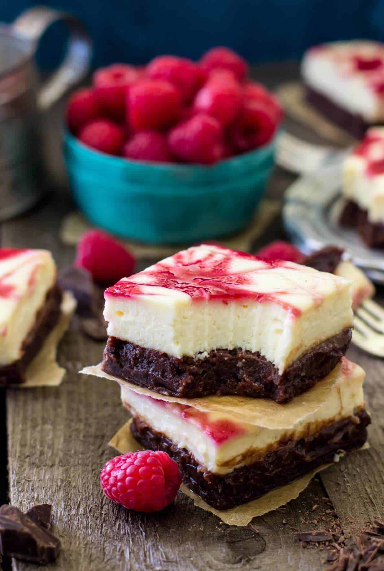 Raspberry swirled Cheesecake Brownies stacked on top of each other with bite missing