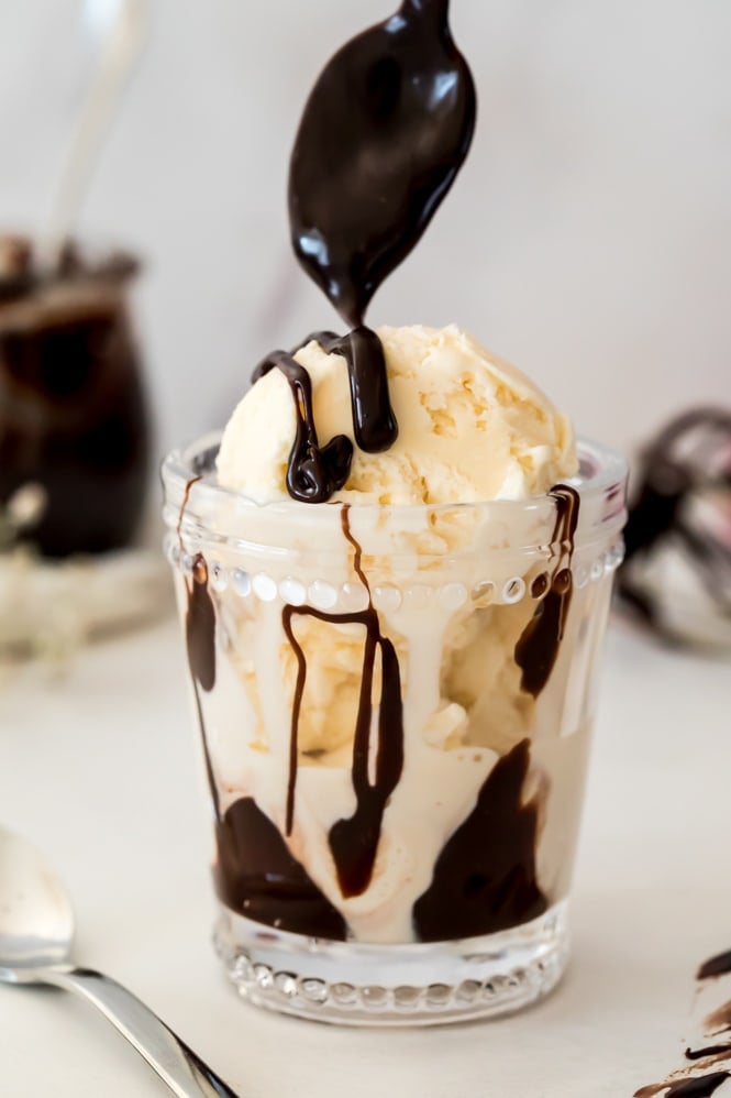 Drizzling hot fudge sauce over vanilla ice cream