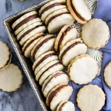 Vanilla and chocolate sandwich cookies, lined up in a silver serving tray