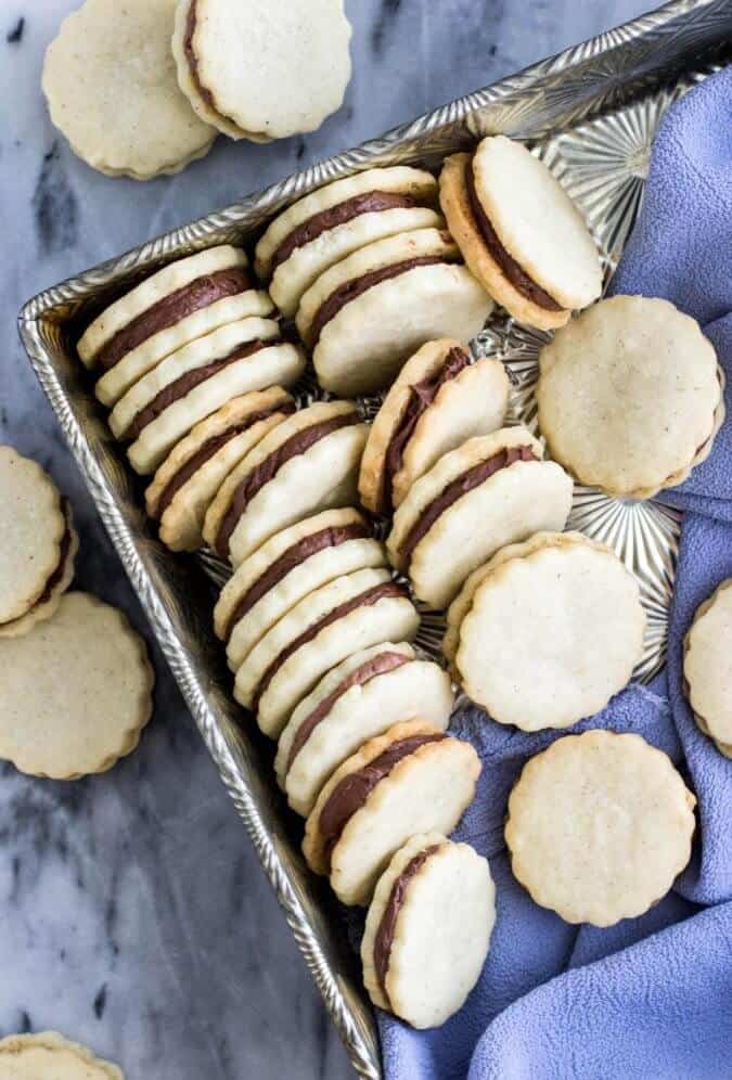 Vanilla and chocolate sandwich cookies, lined up in a silver serving tray