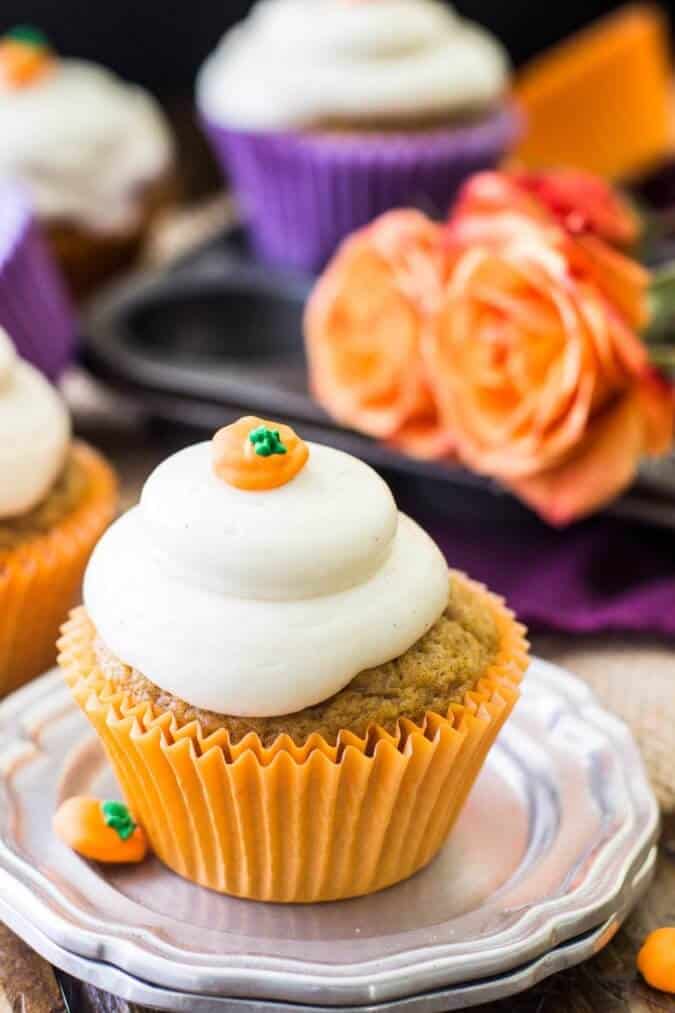 Pumpkin cupcake with cream cheese frosting on a silver plate with orange roses in the background