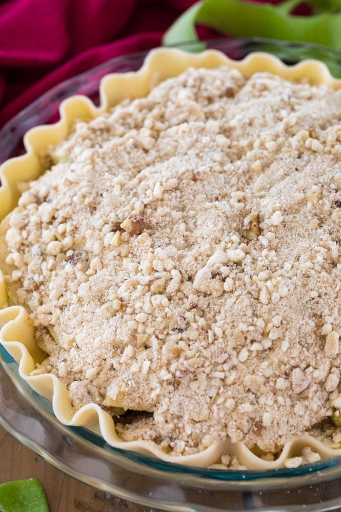 Preparing apple pie: topping crust and filling with walnut crumble