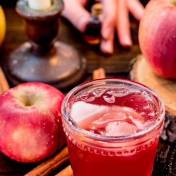 Glass of witch potion, with cinnamon sticks and an apple next to it