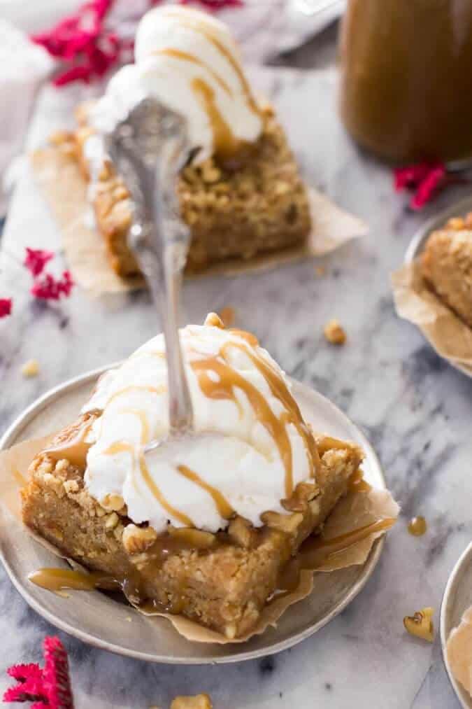 Browned butter maple bar topped with scoop of icing and drizzled with caramel sauce