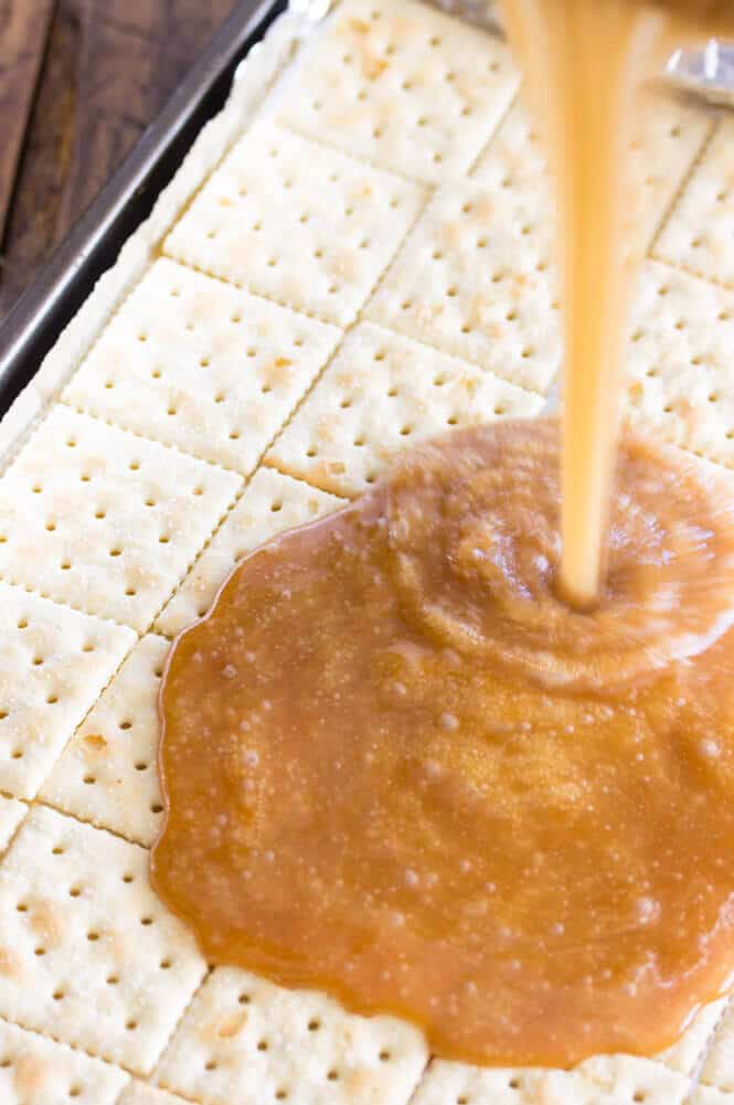 Caramel sauce poured onto saltine crackers in baking sheet