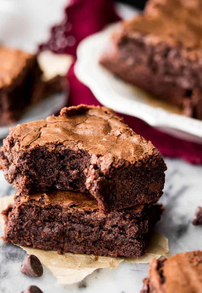 Two brownies stacked on top each other with bite out to show fudgy center