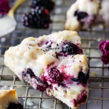 Triple berry scone glazed with icing on cooling rack