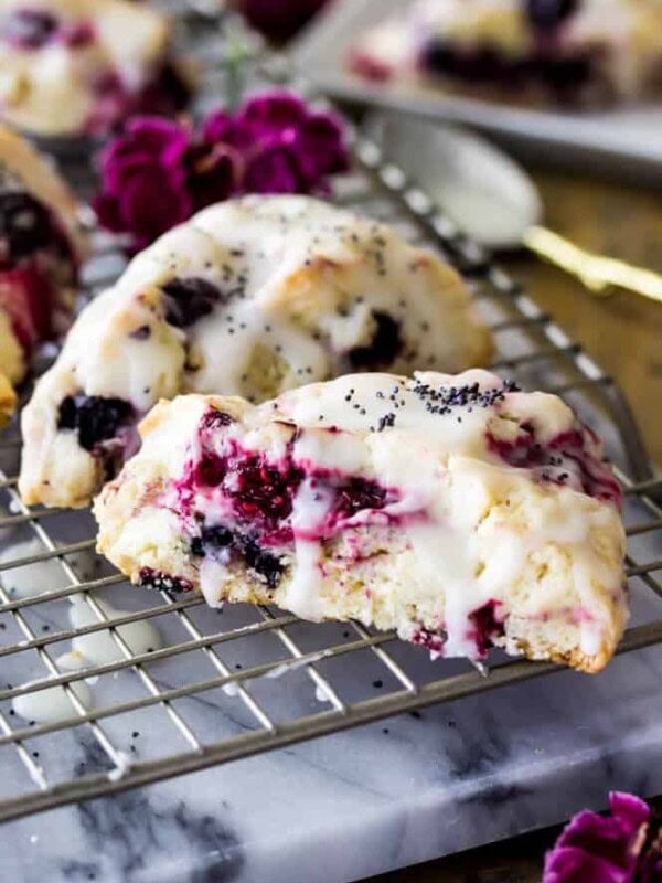 Triple berry scones drizzled with glaze on cooling rack