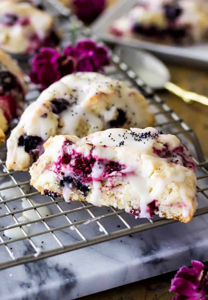 Triple berry scones drizzled with glaze on cooling rack