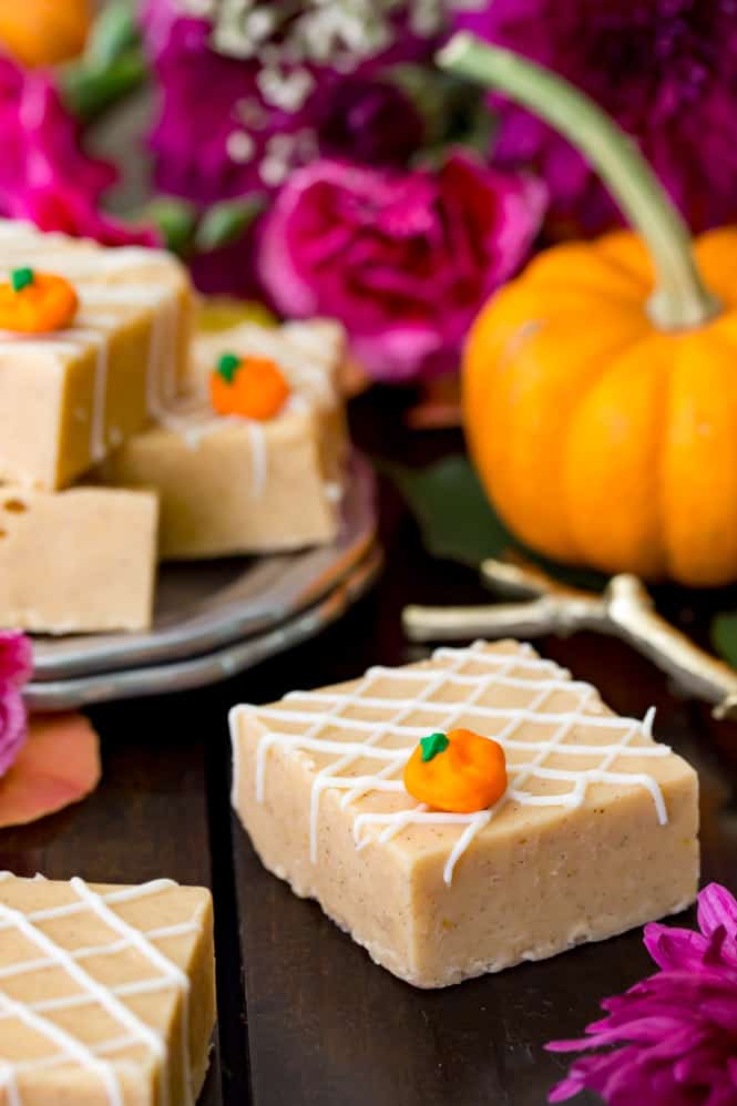 Pumpkin fudge on a table surrounded by flowers and a pumpkin