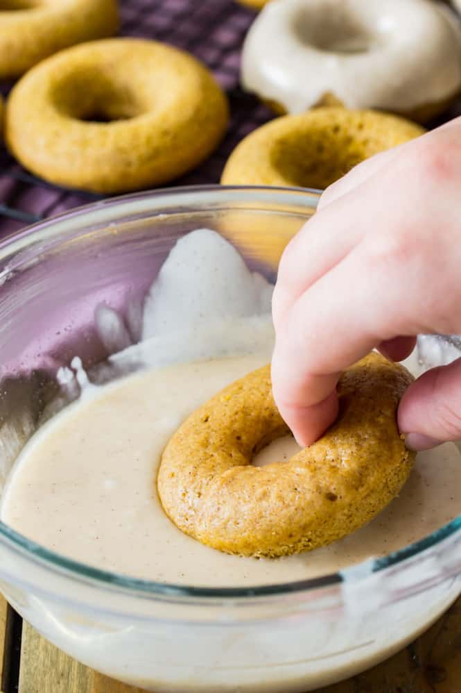 Pumpkin spice donuts dipped in bowl of glaze