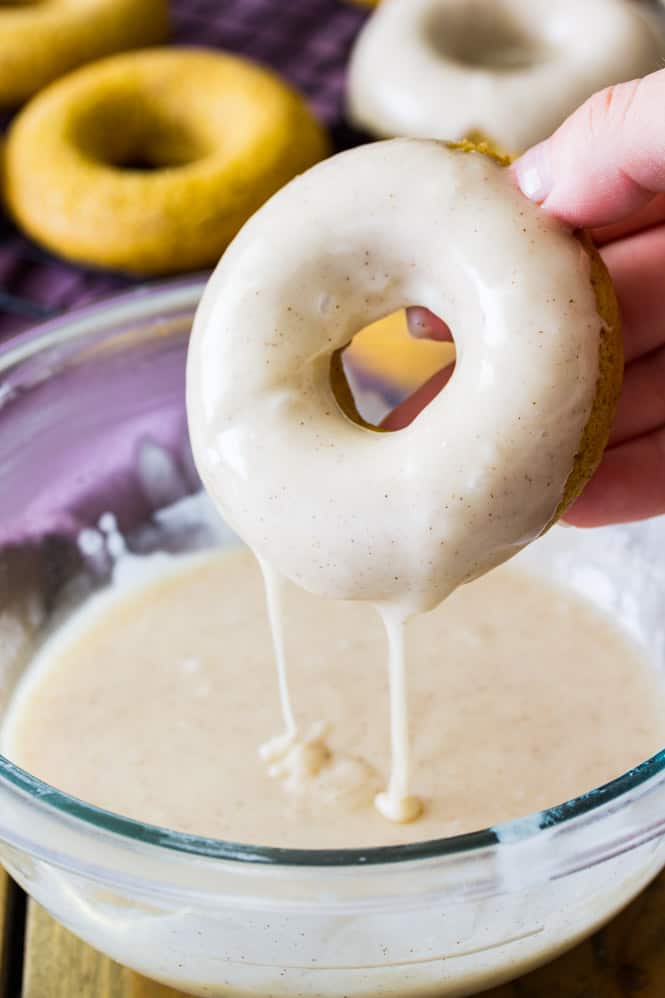 Pumpkin spice donut dipped in bowl of glaze