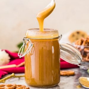 golden caramel sauce dripping off spoon into glass container