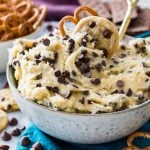 Bowl of cookie dough dip with pretzels and mini chocolate chip cookies in background