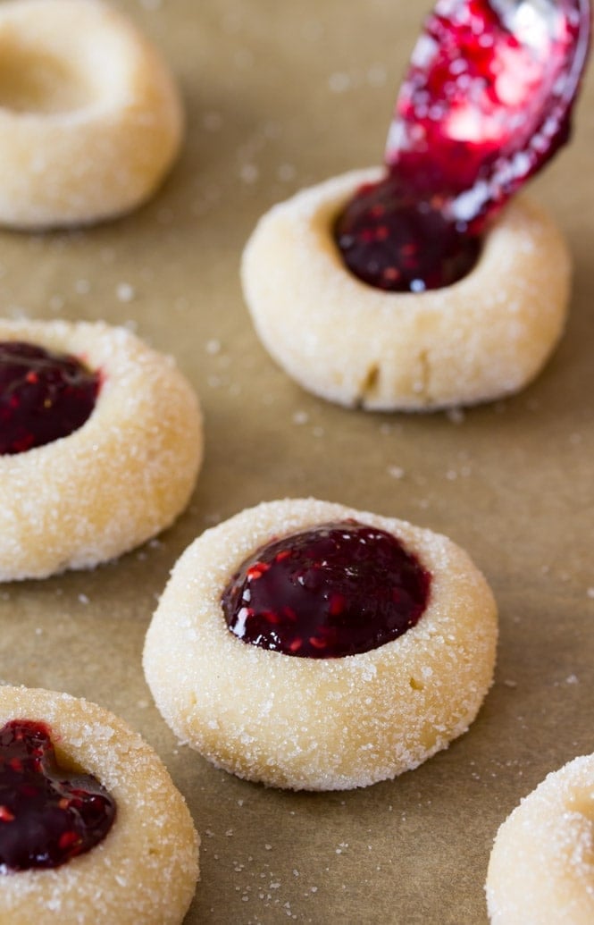Classic thumbprint cookies being filled with raspberry preserves