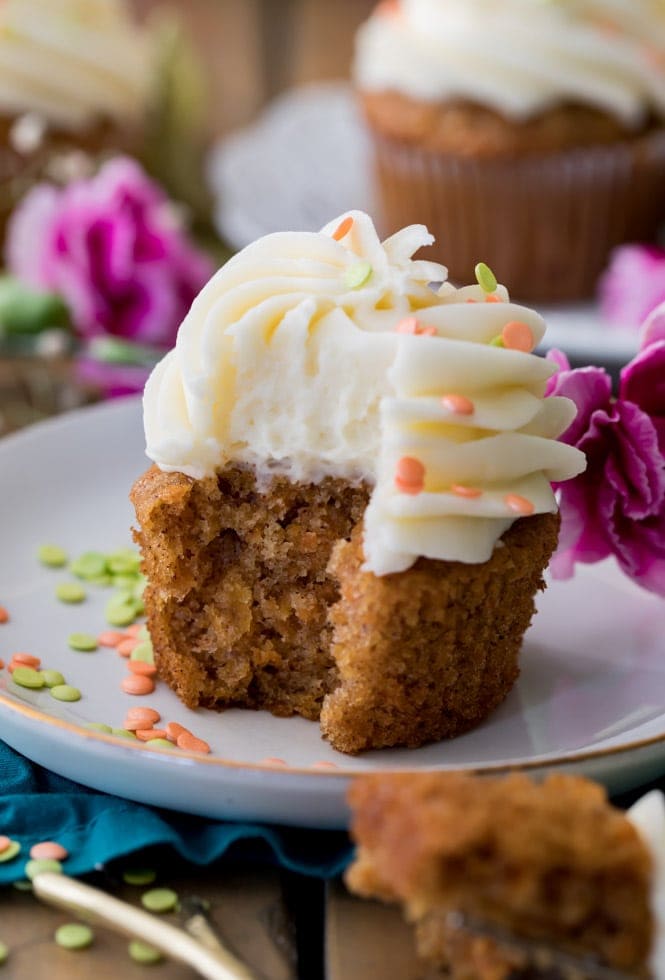 Bite taken out of a carrot cake cupcake with cream cheese frosting