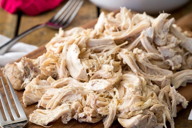 A cutting board loaded with juicy shredded chicken