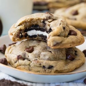 Stack of Oreo stuffed chocolate chip cookie - with bite missing to reveal oreo cookie inside - on plate