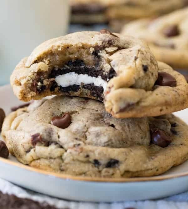 Stack of Oreo stuffed chocolate chip cookie - with bite missing to reveal oreo cookie inside - on plate