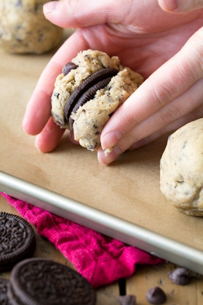 An Oreo Cookie being sandwiched between two pieces of cookie dough