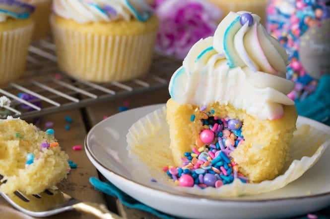Pinata Cupcake with sprinkles spilling out of center onto plate